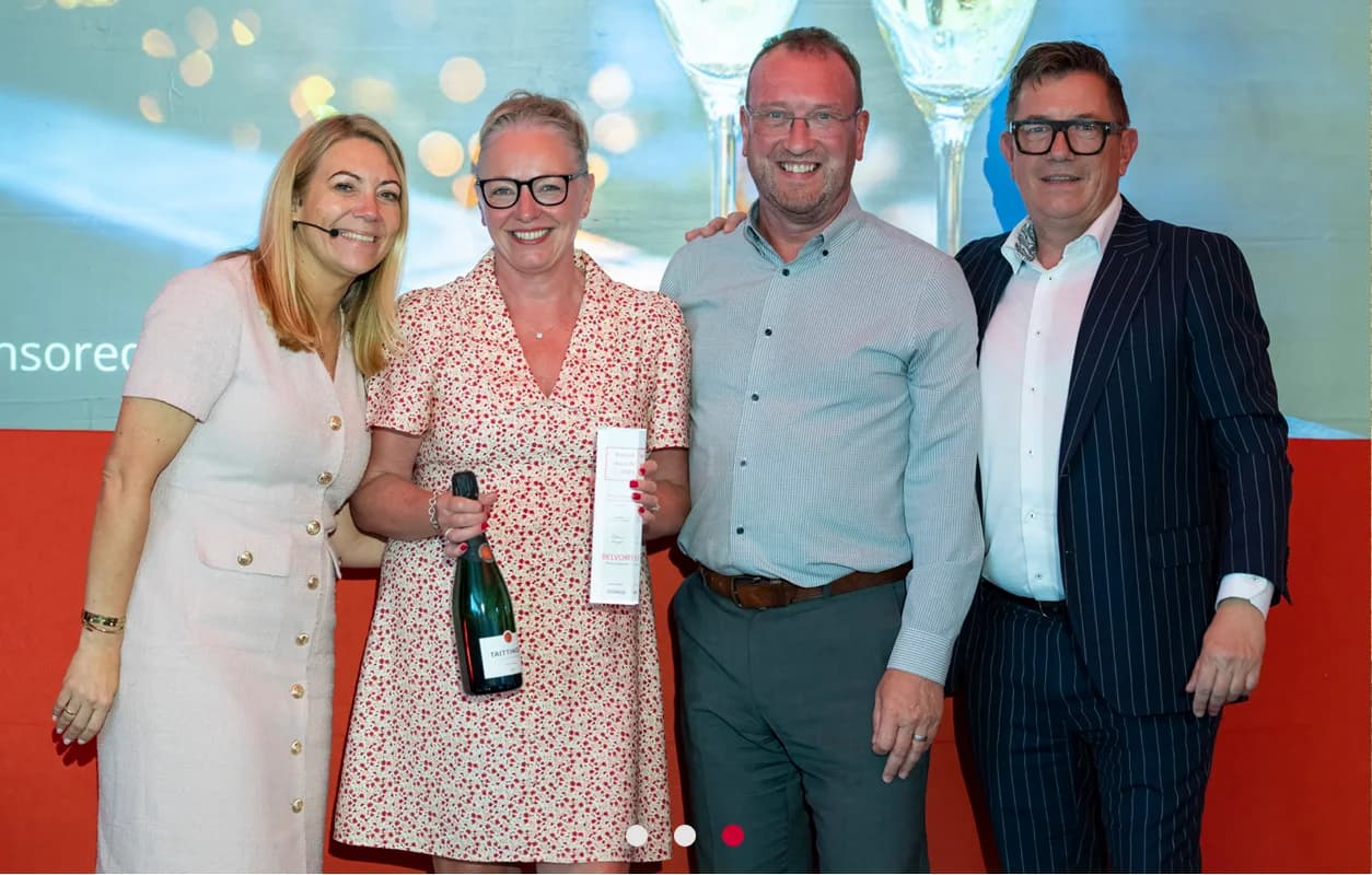 Belvoir franchise owners celebrating an industry award with a champagne bottle and certificate at a UK awards ceremony