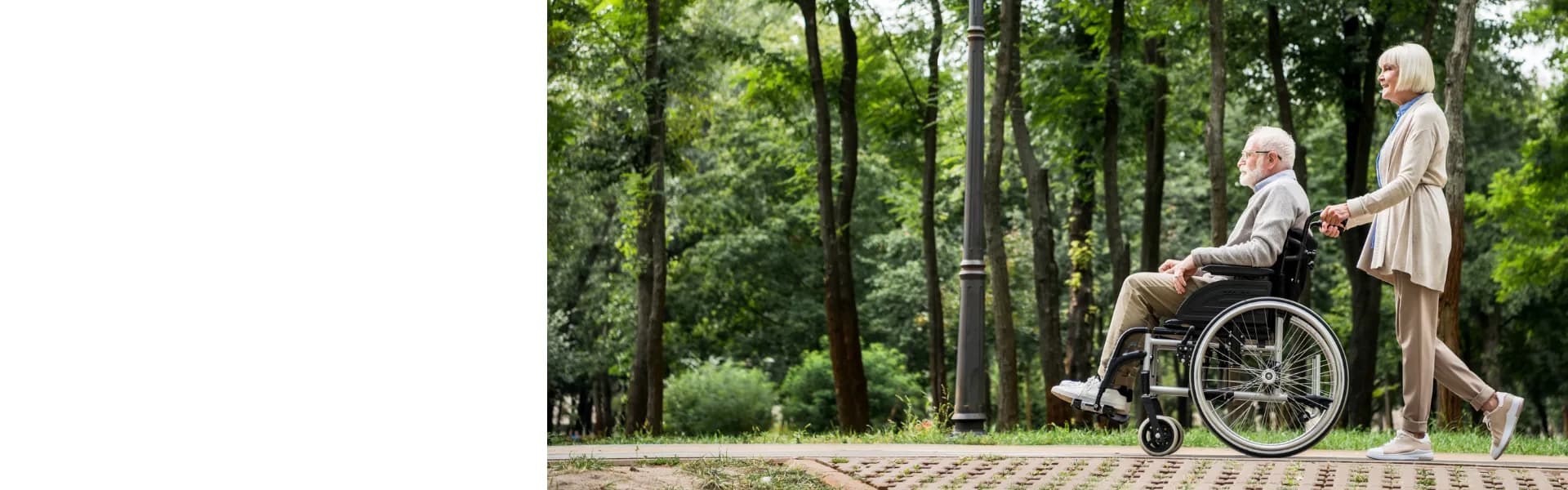 Woman pushing an elderly man in a wheelchair through a leafy green park, representing home care franchise opportunities in the UK.