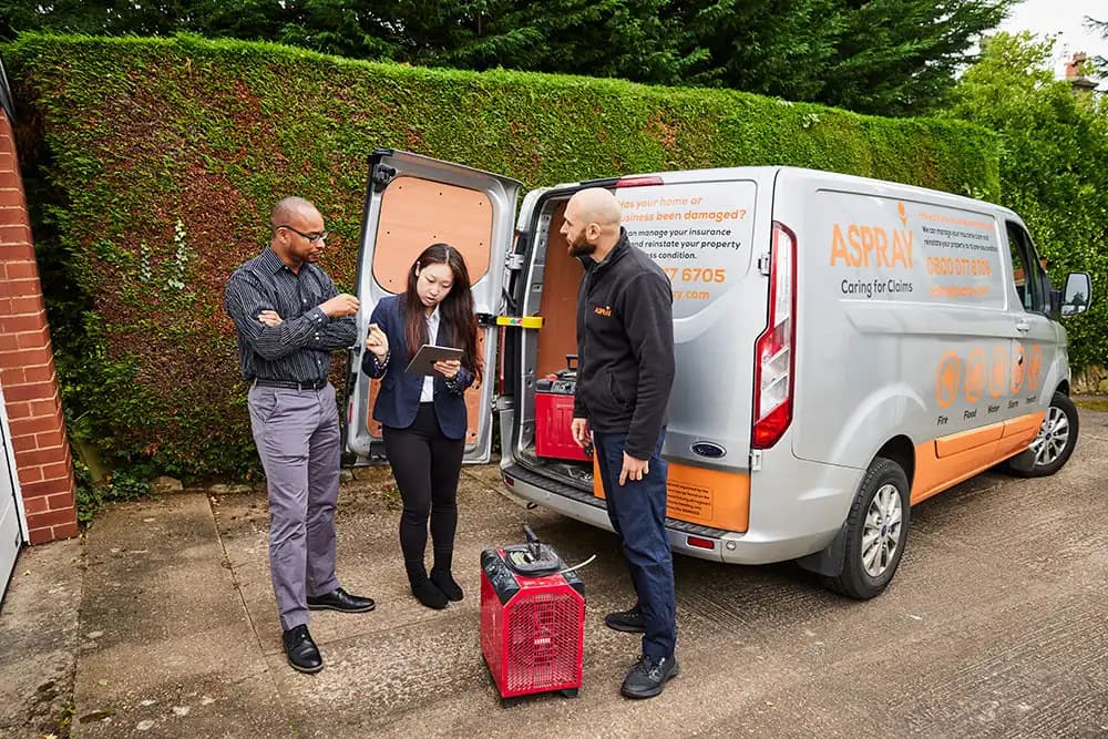 Aspray franchise team managing a property insurance claim on-site with branded van