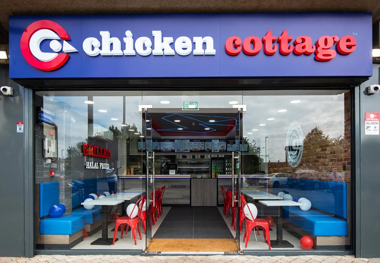 Chicken Cottage shopfront with bright red and white signage, full-glass facade revealing the modern interior with red chairs and 'Grilled Halal Fried' branding
