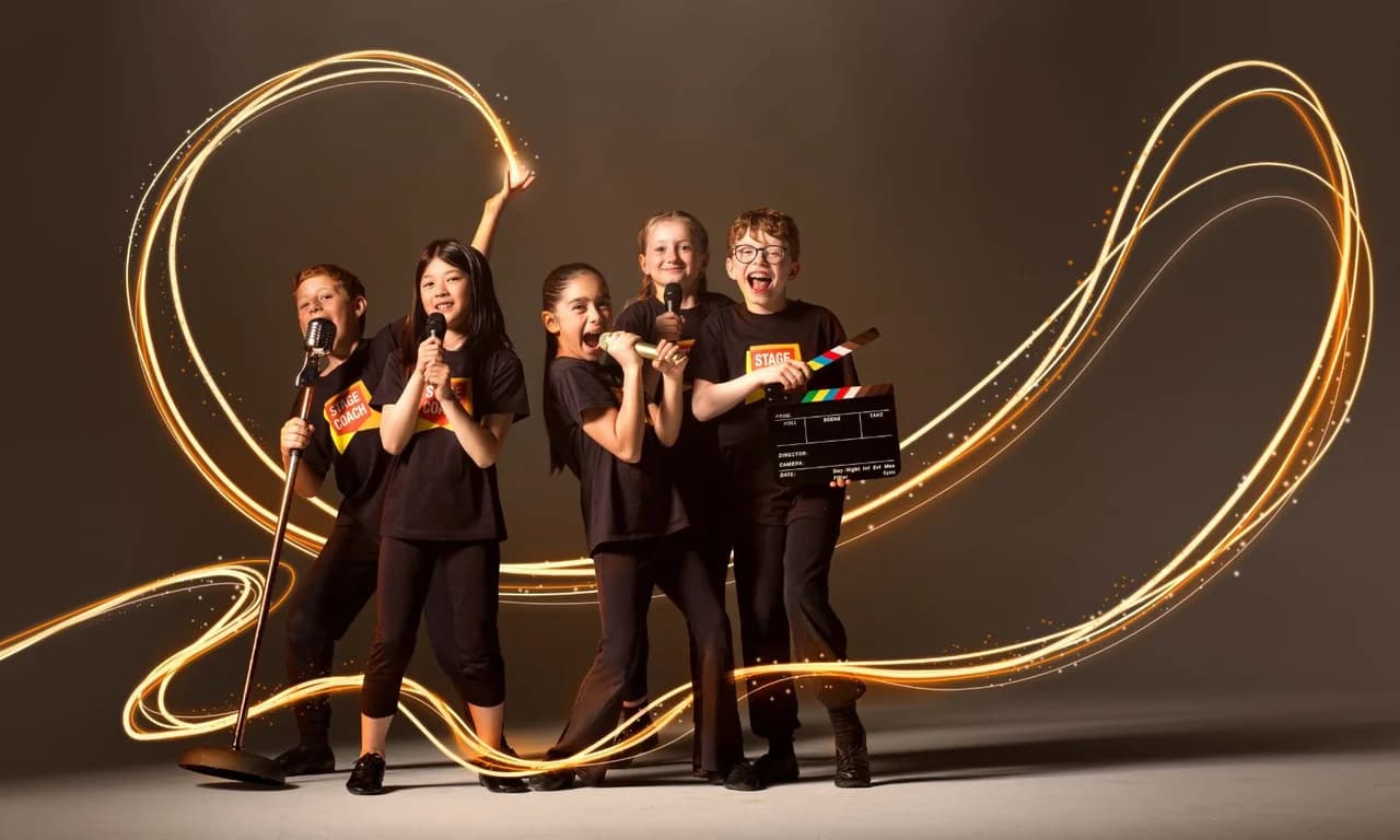 Five Stagecoach Performing Arts students in black tees with orange badge logos posing dramatically with microphones and a film clapperboard, surrounded by swirling gold light trails that suggest a sparkling stage performance