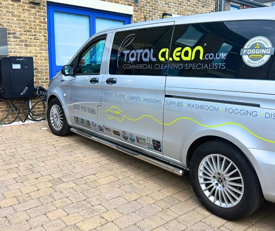Full side view of a silver Mercedes Vito Total Clean franchise van parked outside a depot, with the Total Clean wordmark, a service list (Offices, Floors, Carpets, Windows, Supplies, Washroom, Fogging), the 0207 935 5088 contact number, a 'Decontamination Specialists - Fogging Protection' badge and BICSc/BFA accreditation logos along the lower panel