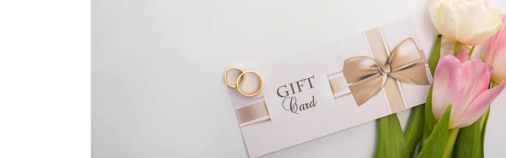 Elegant wedding gift card with gold rings and pink tulips on a light background, representing event and wedding planning franchise opportunities in the UK.
