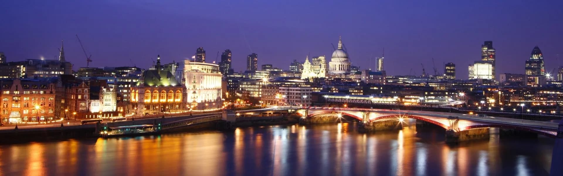 London skyline at night with St Paul's Cathedral, the River Thames and Blackfriars Bridge illuminated, representing franchise opportunities in England.
