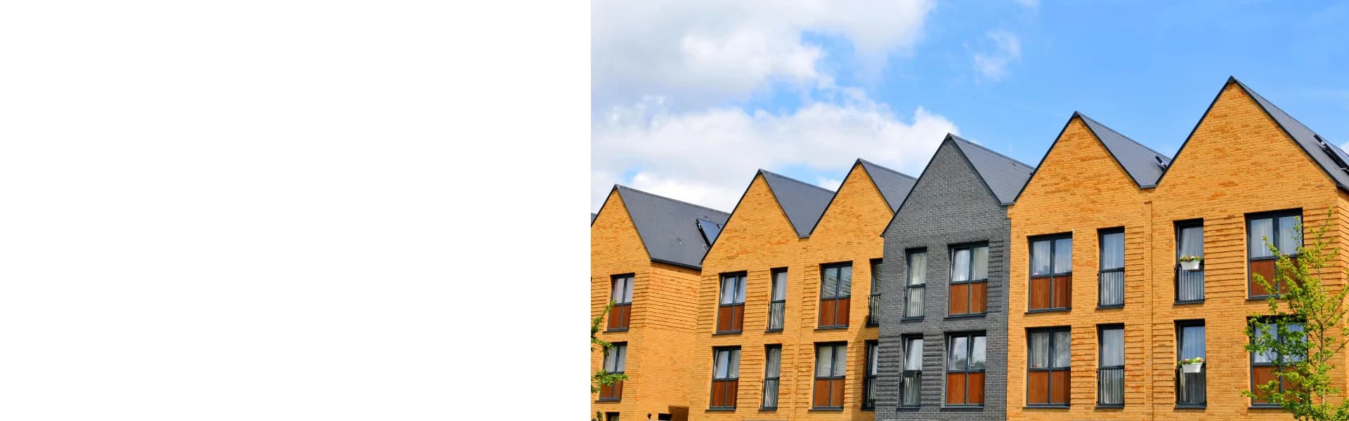 Row of modern townhouses with pitched roofs and yellow and grey brickwork against a blue sky, representing property and estate agency franchise opportunities in the UK.