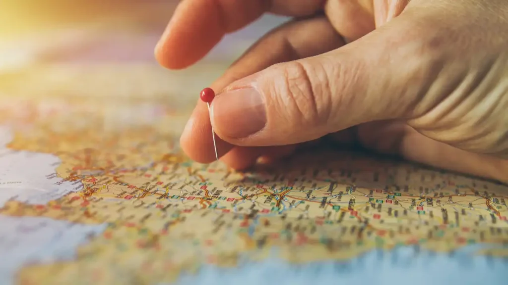 Hand placing a red pin on a UK map to represent franchise location choice