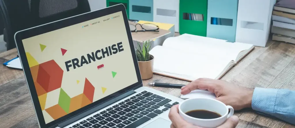 Person researching what a franchise is on a laptop screen while holding a coffee cup