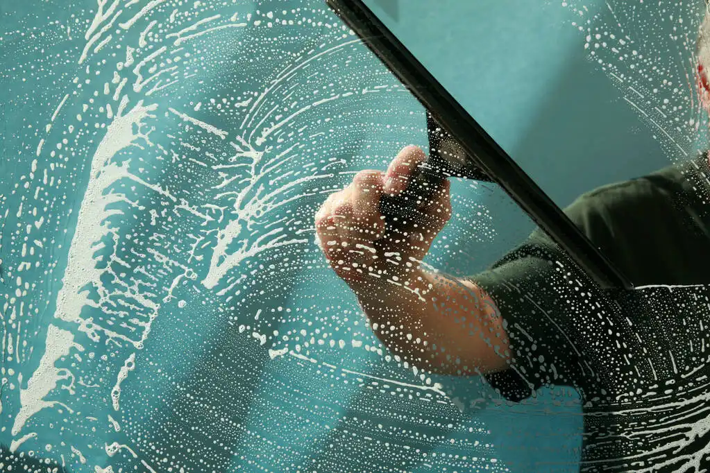 Alice in Windowland Franchise professional window cleaner using squeegee on glass